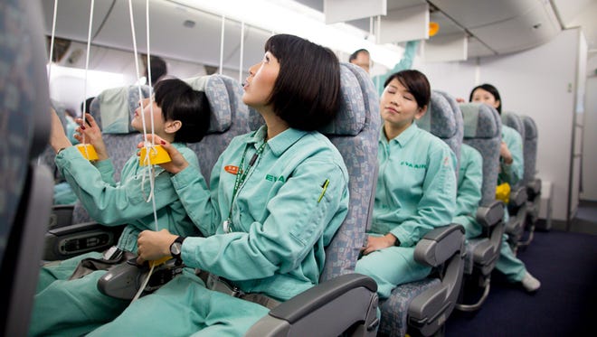 Trainees reach for oxygen masks inside an EVA Air mock cabin simulator. Smokes snarls nostrils and vision alike further ahead in the cabin as fellow trainees work to put out a simulated cabin fire.
