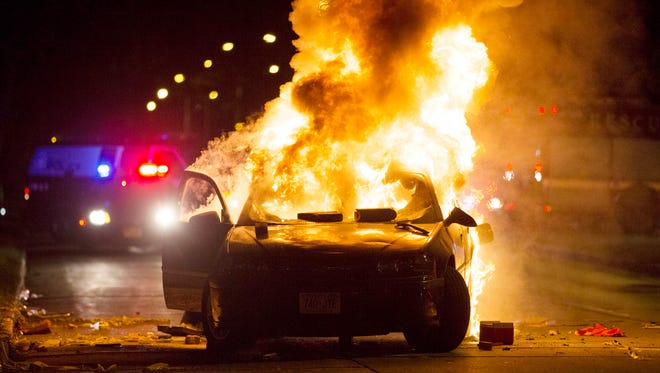 A car burns after violence erupted during a standoff between police and an angry crowd near N. 44th St. and W. Auer Ave.