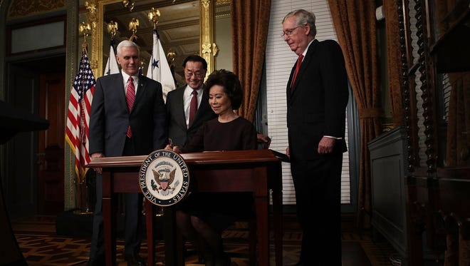 Elaine Chao signs the affidavit of appointment as Vice President Pence, her father, James Chao, and her husband, Senate Majority Leader Mitch McConnell, R-Ky., look on during her swearing-in ceremony on Jan. 31, 2017, in Washington.