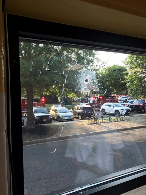 Emergency personnel are seen through a window with a bullet hole in Alexandria, Va.