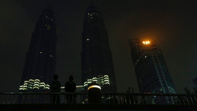 Visitors can barely be seen against of Malaysia's landmark Petronas Twin Towers and surroundings with lights turned off to mark Earth Hour, Saturday in Kuala Lumpur.