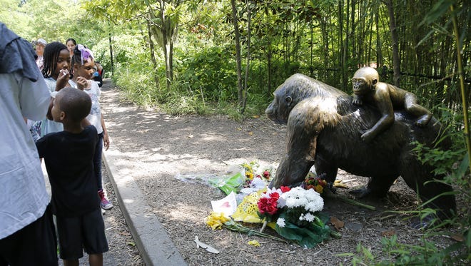 Children look at the flowers and letters left for Harambe Monday after the gorilla was shot and killed Saturday when a 4-year-old boy fell into the Cincinnati Zoo's gorilla exhibit.