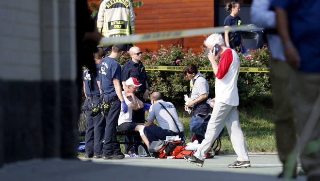 A person is treated by emergency workers  as members of the Republican congressional baseball team look on  following a shooting in Alexandria, Va  14 June 14, 2017. The Republican House majority whip Steve Scalise and at least four others have been shot shot at a congressional baseball game practice session, according to media reports