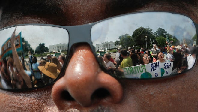 The White House and marchers are reflected in a participant's sunglasses during a demonstration in Washington on April 29, 2017.