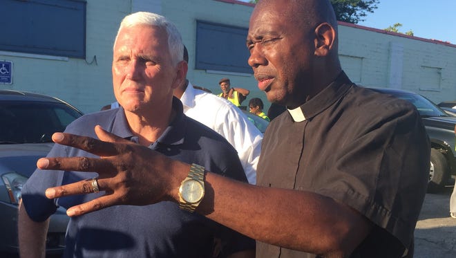 Gov. Mike Pence (left) and the Rev. Charles Harrison talk about violence at the intersection of 29th and Dr. Martin Luther King Jr. streets in Indianapolis on Monday, July 11, 2016.
