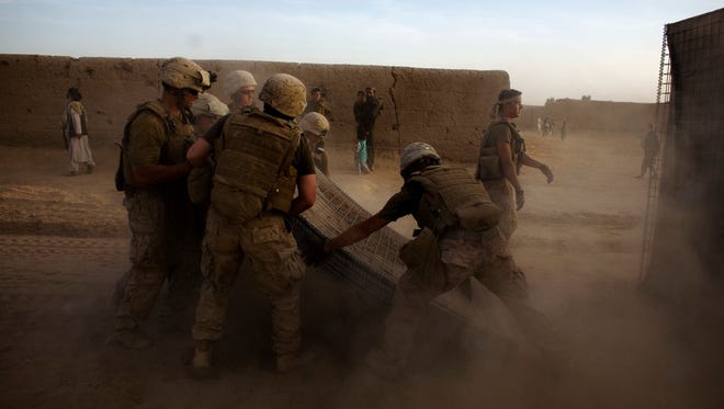 In this file image taken on March 15, 2010, in Marjah, Marines of the First Battalion, Sixth Marine Regiment build a barrier around their base.