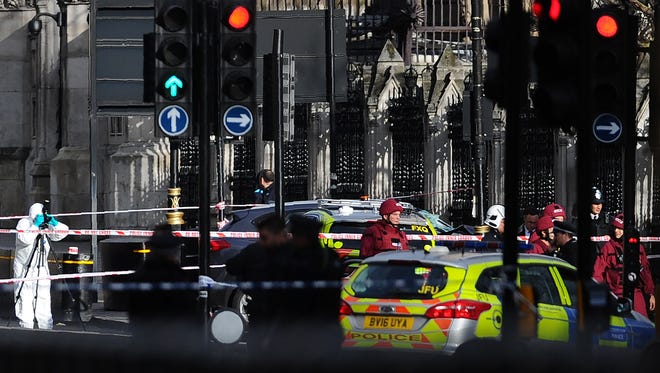 Armed police officers stand guard as forensics officers work around a grey vehicle that crashed into the railings of the Houses of Parliament in central London on March 22, 2017, during an emergency incident.