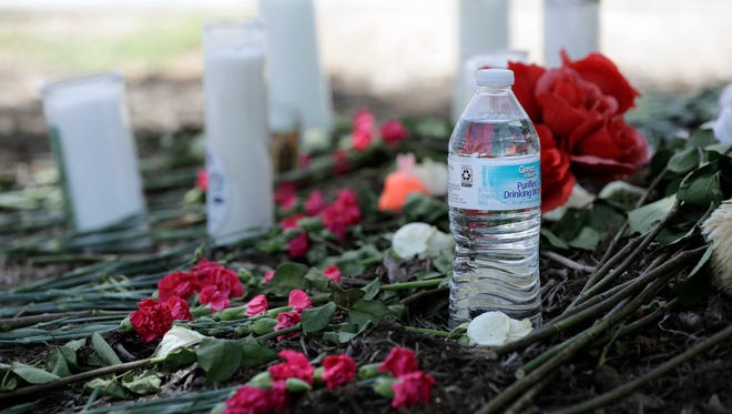 A bottle of water, flowers, candles, and stuffed animals help form a makeshift memorial in the parking lot of a Walmart store in San Antonio, July 24, 2017.