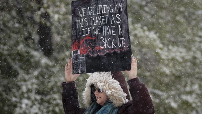 Leah Stein of Parker, Colo. holds a sign while protesting at the People's Climate March in Denver.
