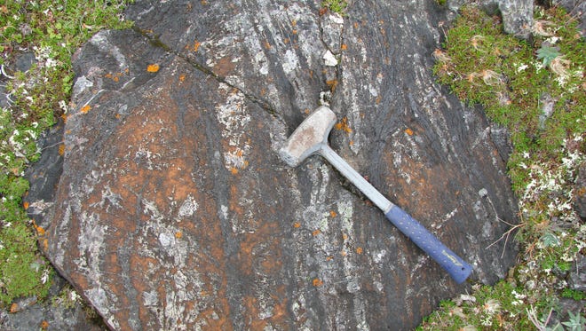 Rounded-shaped laminated iron-carbonate (orange) with white chert and black oxide and silicate layers in the Nuvvuagittuq Supracrustal Belt, Quebec, Canada. This outcrop may have been part of a hydrothermal vent structure.
