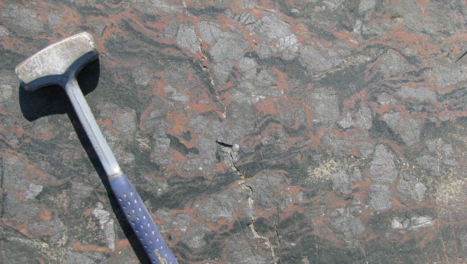 The volcanic rock with an age of at least 3,770 million- year-old and possibly up to 4,280 million-year-old, now metamorphosed with fist-sized purple rounded garnet crystals and surface rust on Fe-silicate minerals (black). Nuvvuagittuq Supracrustal Belt in Quebec, Canada.
