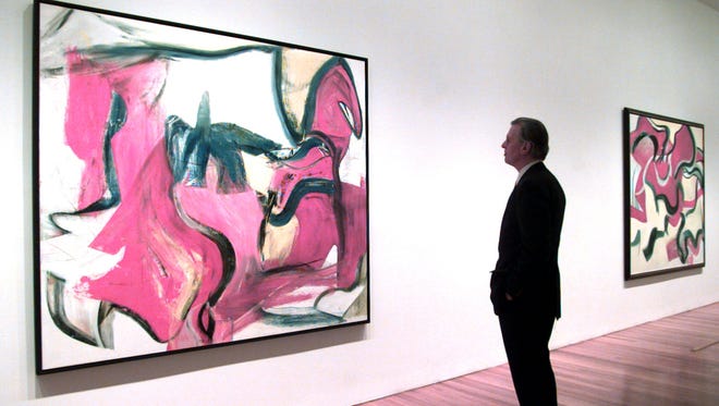 John Elderfield, curator at large at the Museum of Modern Art, looks at paintings by Willem de Kooning at the museum in New York Wednesday, March 19, 1997. De Kooning, 92, died Wednesday morning at his studio in East Hampton, N.Y. The abstract expressionist's paintings shocked the mid-century art world with their slashes of color and melange of abstraction and realism. The painting on the left is "Untitled Xll" from 1982. (AP Photo/Mark Lennihan)