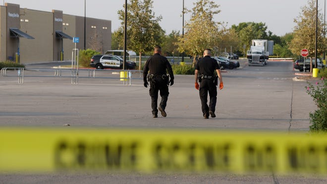 San Antonio police officers investigate the scene where multiple people were found dead in a tractor-trailer loaded with at least 30 others outside a Walmart store in stifling summer heat in San Antonio.