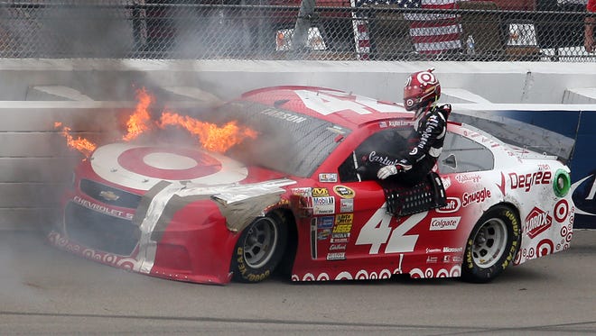 Kyle Larson exits his car after it caught fire following a crash in Turn 4 at the 2014 Pure Michigan 400 at Michigan International Speedway.