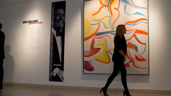 A Christie's employee poses for photographers by walking past the late Dutch American artist Willem de Kooning's painting "Untitled XVII", next to an image of the late American crooner Andy Williams at the auction house's offices in London, Friday, Feb. 8, 2013.  The piece is part of a post-war and contemporary art collection of around 70 works owned by Williams that are estimated to fetch around $30 million (19 million pounds, 22million euro) when they feature in an auction in New York on May 15 and 16.  (AP Photo/Matt Dunham)