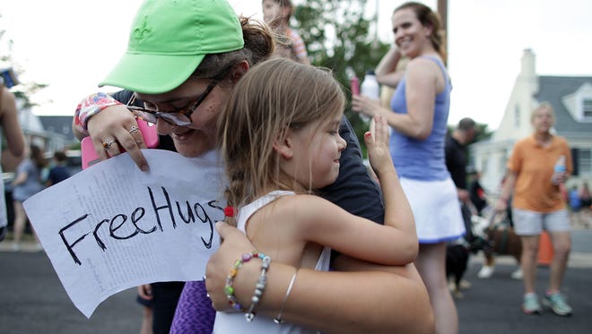 Marianna Oppman gives out free hugs as local residents gather outside The Anglican Catholic Church St. Andrew & St. Margaret of Scotland to show solidarity after a shooting at the Eugene Simpson Stadium Park in Alexandria, Va.