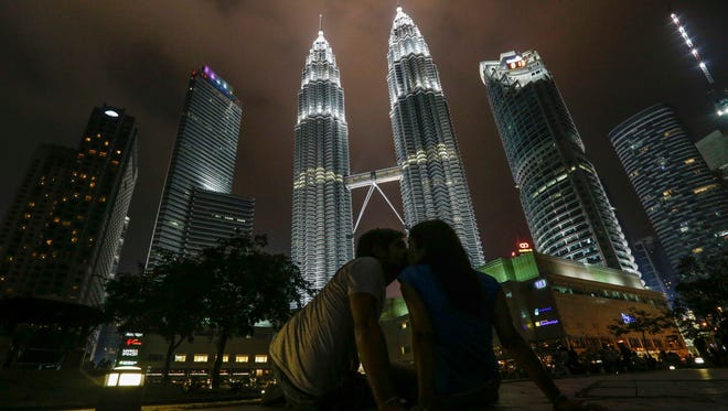 Tourists kiss in front of Malaysia's landmark Petronas Twin Towers with lights on before marking Earth Hour 2016 in Kuala Lumpur, Malaysia.