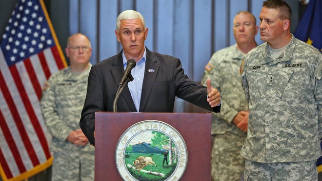 Governor Mike Pence, center, talks about authorizing the arming of soldiers at Indiana National Guard facilities and recruiting sites statewide, while speaking to the press at a press conference at the Indiana National Guard Joint Force Headquarters, Sunday, July 19, 2015. He is joined by Col. Timothy Thombleson, from left behind him, Col. Ronald Westfall, and Indiana Adjutant General Major General Corey Carr.