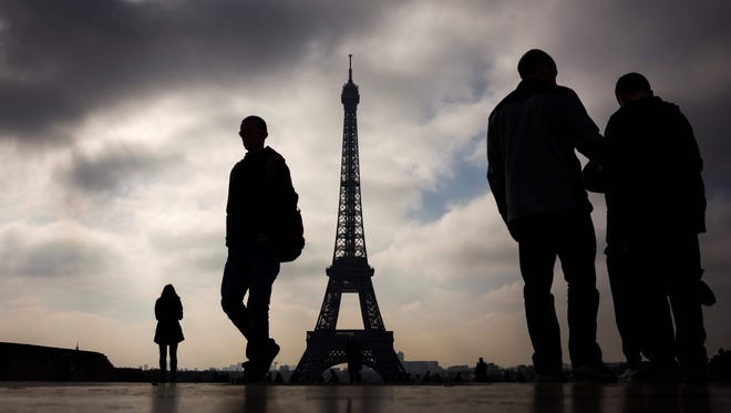 People walk in front of the Eiffel tower in Paris.