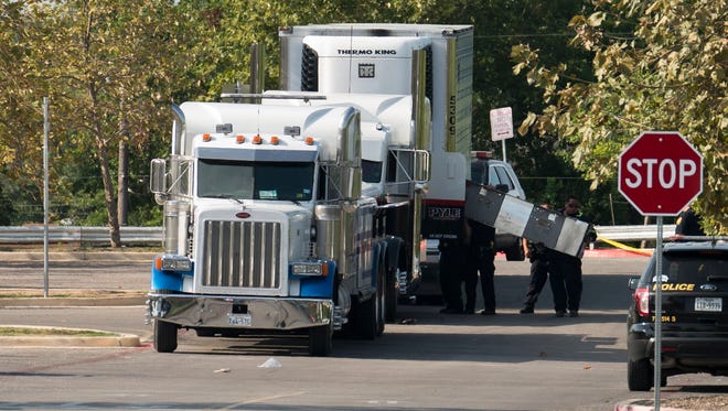 A truck that contained dozens of suspected immigrants, several of whom died, is towed from the scene in San Antonio.