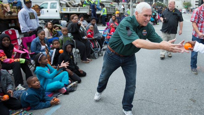 Mike Pence, Indiana Governor, hands out toy balls to spectators at the Circle City Classic parade, Indianapolis, Saturday, September 26, 2015. The event marks the annual Classic football game, this year pitting Central State University against Kentucky State University at Lucas Oil Stadium.
