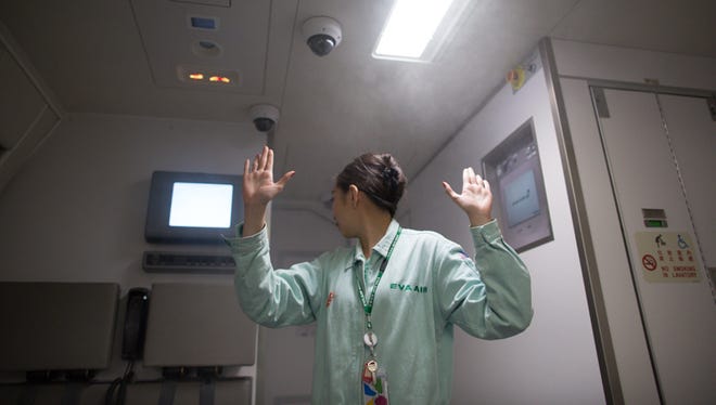 A trainee keeps a careful eye on her colleague while simulatenously appealing to passengers - fellow students, in this case - to stay calm as smoke from a restroom fire begins to fill the cabin simulator.