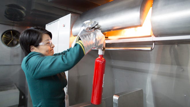 Grace Yang, EVA Air's Executive Vice President of Cabin Service, demonstrates putting out a live fire in a mock overhead luggage bin. The airline recently added the unusual live fire-training space, which can replicate controlled fires inside restrooms, seat backs, and luggage bins among other locations.