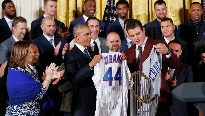 President Obama holds up a personalized Chicago Cubs jersey presented to him by Anthony Rizzo.