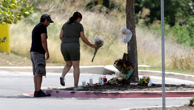 A couple visits a make-shift memorial in the parking lot of a Walmart store on July 24, 2017, near the site where authorities Sunday discovered a tractor-trailer packed with immigrants outside a Walmart in San Antonio. Several people died and others hospitalized after being crammed into a sweltering tractor-trailer in the midsummer Texas heat, according to authorities in what they described as an immigrant-smuggling attempt gone wrong.