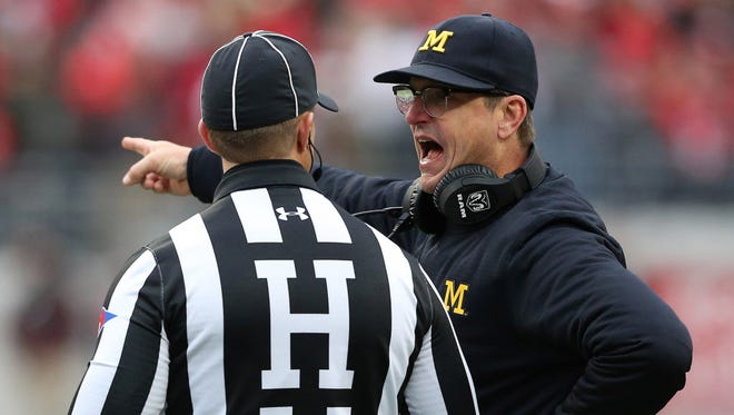 Michigan head coach Jim Harbaugh discusses a call with a referee during the third quarter of the Wolverines' game against Ohio State.