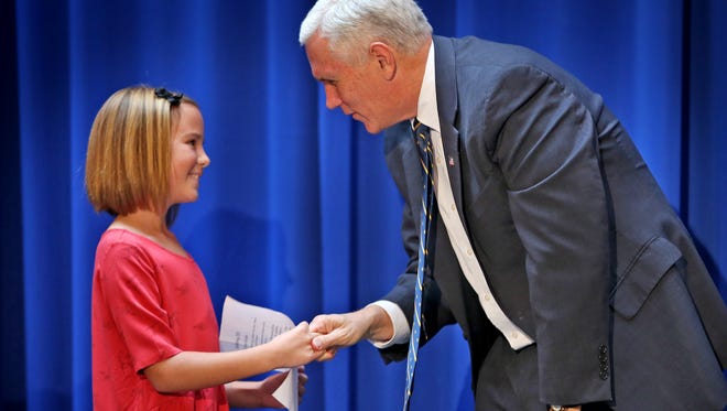 After New Briton Elementary fourth grader Jenna Grubb, left, read her first place Hoosier Bicentennial Celebration Essay, Governor Mike Pence congratulates her, during the Statehood Day Celebration at the Statehouse, Friday, December 11, 2015.  This begins the celebration of Indiana's 199th birthday.