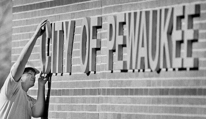 Russ Holeman of Ford Construction of Waukesha attaches the "C" to the side of Pewaukee's City Hall on April 8, 1999. Voters in the former the Town of Pewaukee OK'd changing the municipality's status to thwart continued annexation efforts by the Village of Pewaukee.