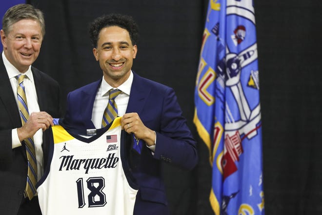 Bill Scholl, left, Marquette vice president and director of athletics, gives Shaka Smart a jersey Monday, March 29, 2021, at the Al McGuire Center in Milwaukee. Smart is the new NCAA college head men's basketball coach at Marquette. (Ebony Cox/Milwaukee Journal-Sentinel via AP)